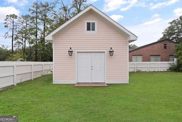 rear view of house featuring a lawn and an outdoor structure