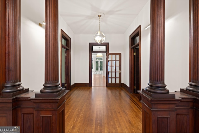 foyer with decorative columns, french doors, a notable chandelier, and hardwood / wood-style flooring