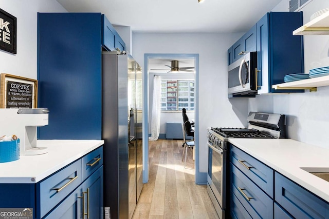 kitchen with ceiling fan, blue cabinets, stainless steel appliances, and light wood-type flooring