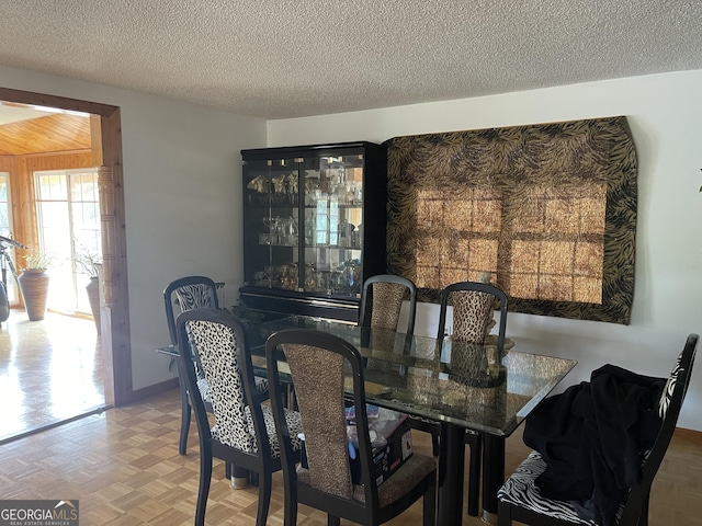 dining area with parquet flooring, a textured ceiling, and wooden walls