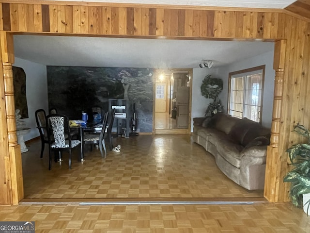 living room featuring wood walls and parquet flooring