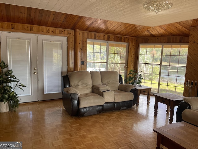 living room with light parquet flooring, wood walls, french doors, and vaulted ceiling