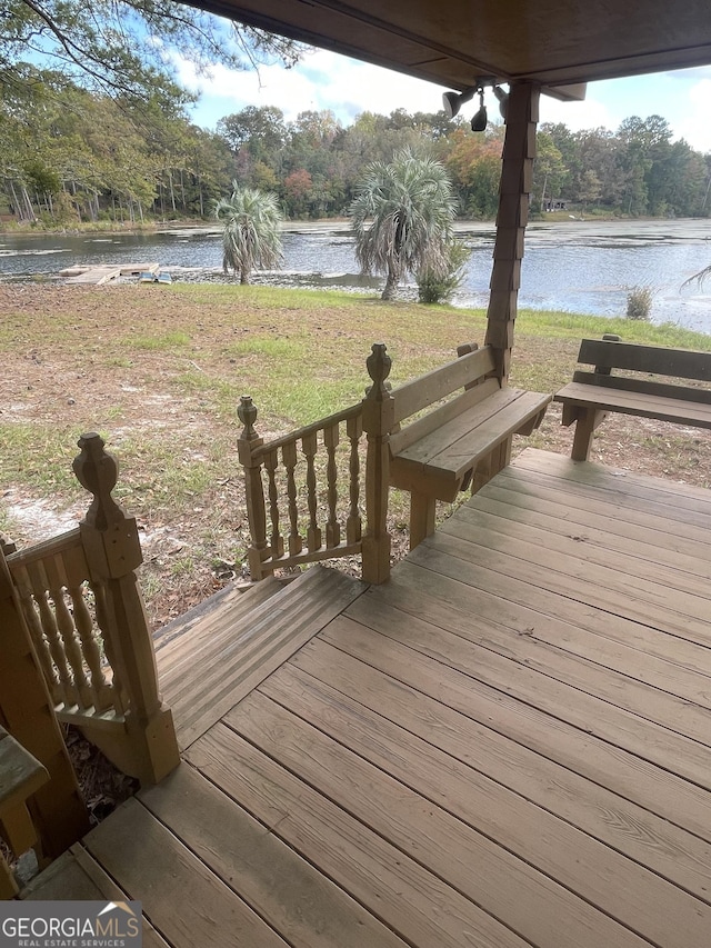 wooden deck with a lawn and a water view