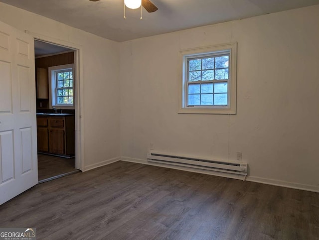 empty room featuring ceiling fan, dark hardwood / wood-style flooring, sink, and a baseboard radiator