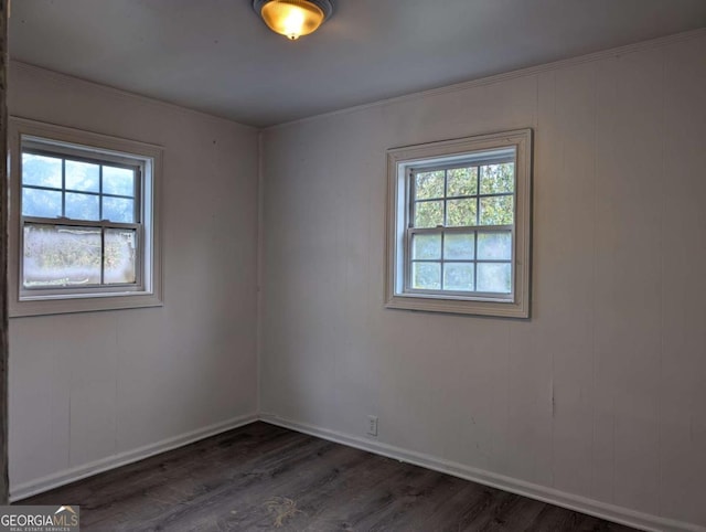 unfurnished room featuring plenty of natural light, dark hardwood / wood-style floors, and ornamental molding