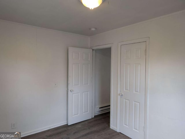 unfurnished bedroom with dark hardwood / wood-style flooring, a baseboard radiator, and crown molding