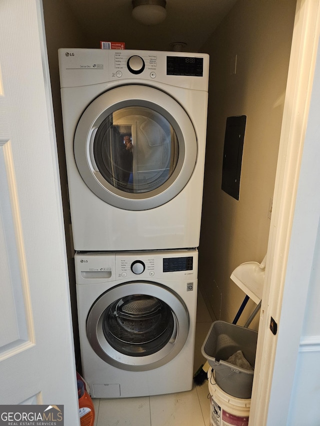 laundry room with tile patterned flooring and stacked washer / drying machine