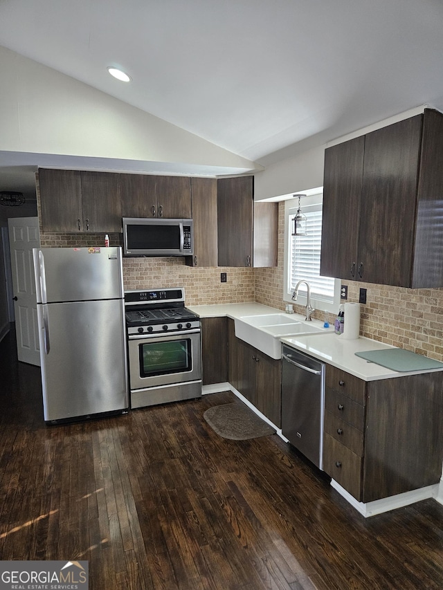 kitchen featuring appliances with stainless steel finishes, tasteful backsplash, dark brown cabinetry, dark wood-type flooring, and lofted ceiling