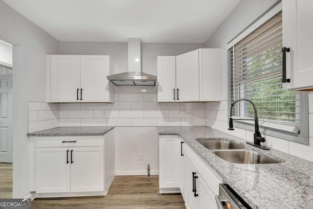 kitchen with backsplash, white cabinetry, sink, and wall chimney exhaust hood