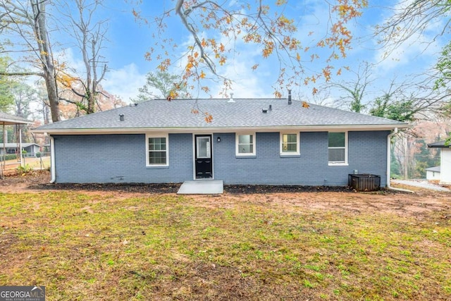 back of property with central AC and a lawn