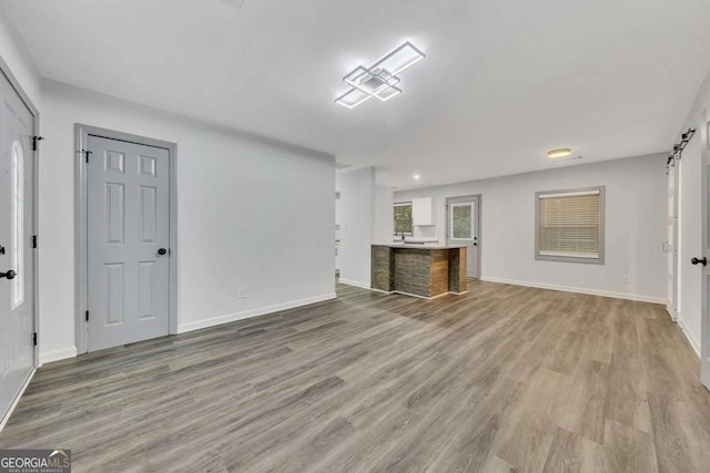 unfurnished living room featuring a barn door and light hardwood / wood-style flooring