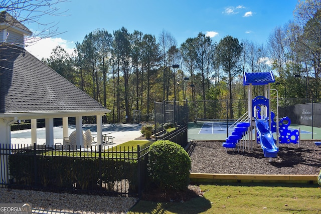 view of play area featuring tennis court and a yard