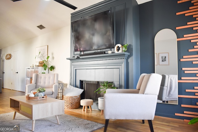 living area featuring high vaulted ceiling, wood-type flooring, and a tile fireplace