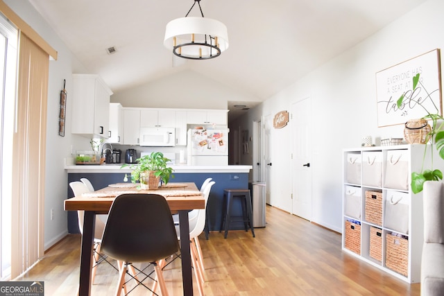 dining space featuring lofted ceiling and light wood-type flooring