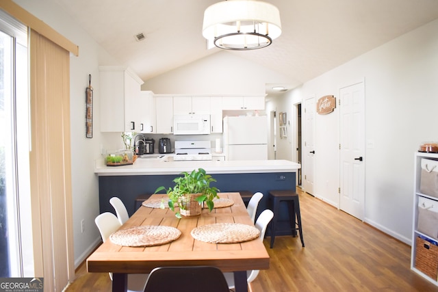 dining room featuring hardwood / wood-style floors, lofted ceiling, and sink