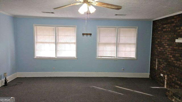 spare room featuring ceiling fan, dark colored carpet, brick wall, a textured ceiling, and ornamental molding