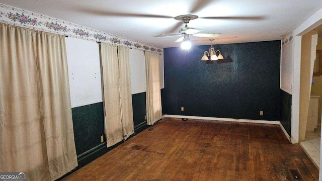 unfurnished bedroom featuring ceiling fan with notable chandelier and dark wood-type flooring