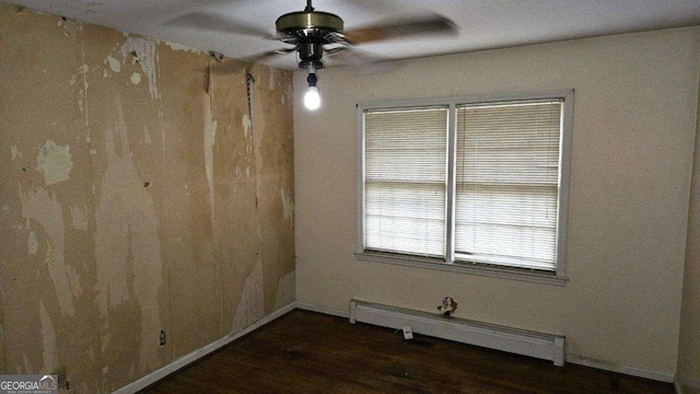 empty room featuring ceiling fan, dark hardwood / wood-style flooring, and a baseboard heating unit