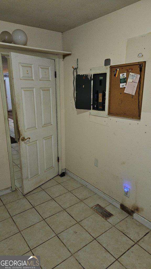 unfurnished room featuring electric panel and tile patterned flooring