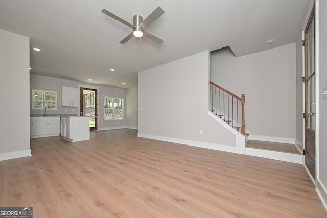 unfurnished living room featuring sink, ceiling fan, and light hardwood / wood-style flooring