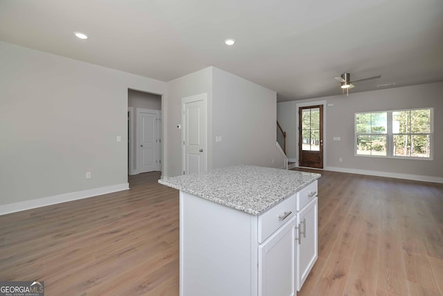 kitchen with white cabinetry, light stone counters, light hardwood / wood-style flooring, and a center island