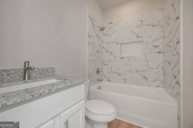 full bathroom with tiled shower / bath combo, vanity, hardwood / wood-style floors, and toilet