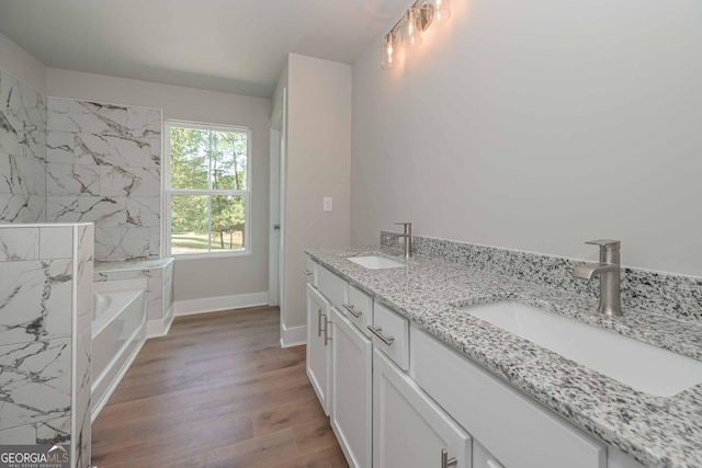 bathroom with hardwood / wood-style flooring, vanity, and a bathing tub