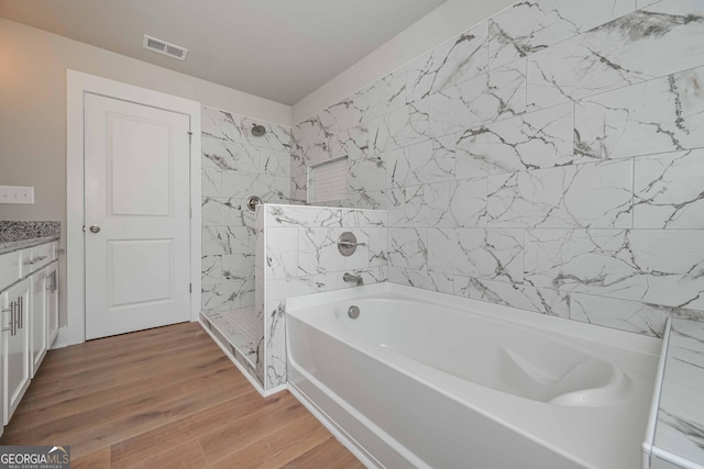 bathroom with hardwood / wood-style flooring, plus walk in shower, tile walls, and vanity