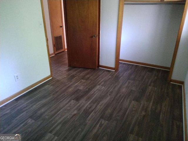 unfurnished bedroom with dark wood-type flooring and a closet