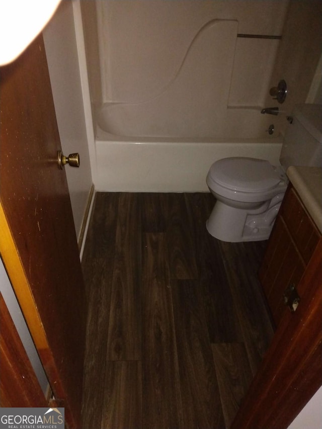 bathroom featuring washtub / shower combination, hardwood / wood-style flooring, and toilet