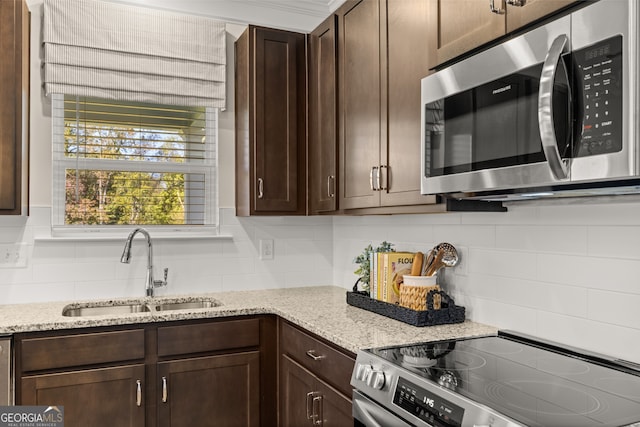 kitchen featuring decorative backsplash, light stone countertops, sink, and appliances with stainless steel finishes