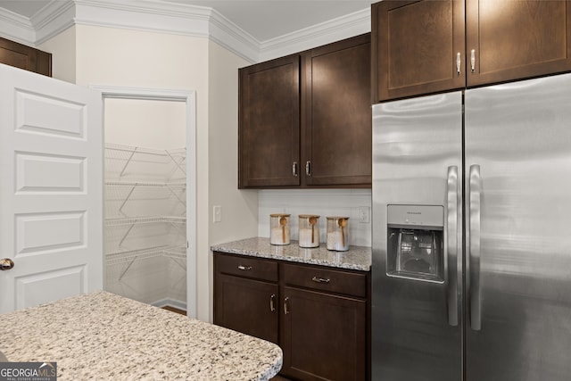 kitchen with light stone counters, stainless steel fridge with ice dispenser, ornamental molding, and dark brown cabinetry