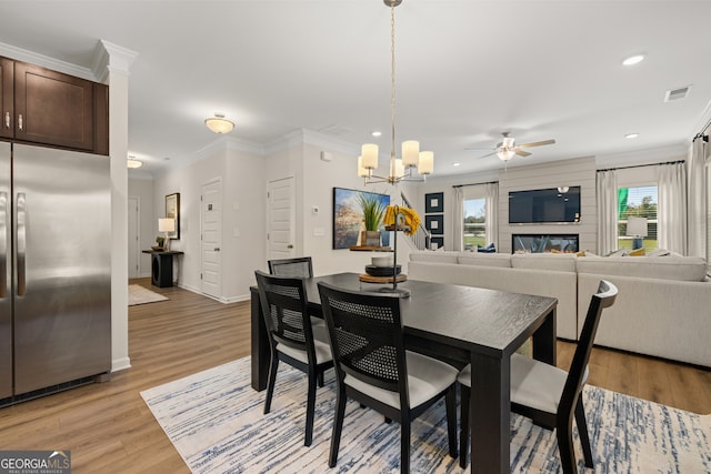 dining space featuring plenty of natural light, crown molding, ceiling fan with notable chandelier, and light hardwood / wood-style flooring