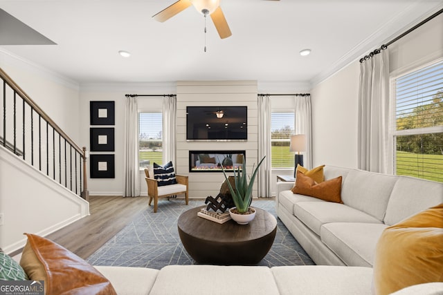 living room with light hardwood / wood-style floors, crown molding, and a healthy amount of sunlight