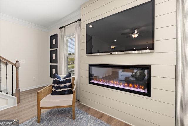 sitting room with crown molding, ceiling fan, and wood-type flooring