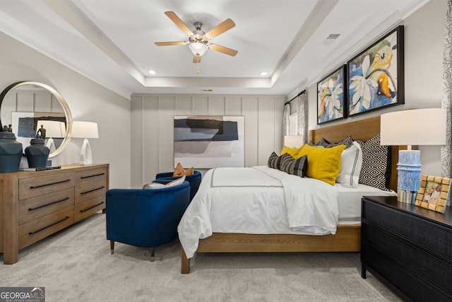 bedroom with light carpet, a tray ceiling, and ceiling fan