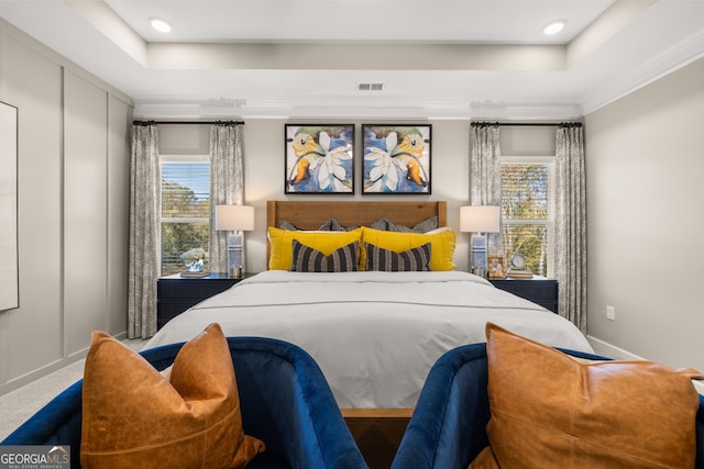 carpeted bedroom with a raised ceiling and crown molding