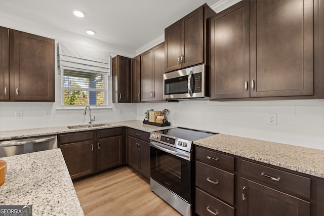 kitchen featuring light stone countertops, appliances with stainless steel finishes, crown molding, sink, and light hardwood / wood-style floors