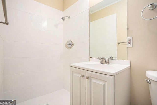 bathroom with a tile shower, vanity, and toilet