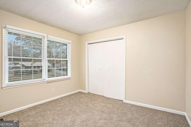 unfurnished bedroom featuring carpet, a textured ceiling, and a closet