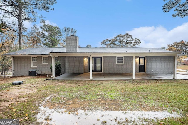 back of house with cooling unit, a patio area, and a lawn