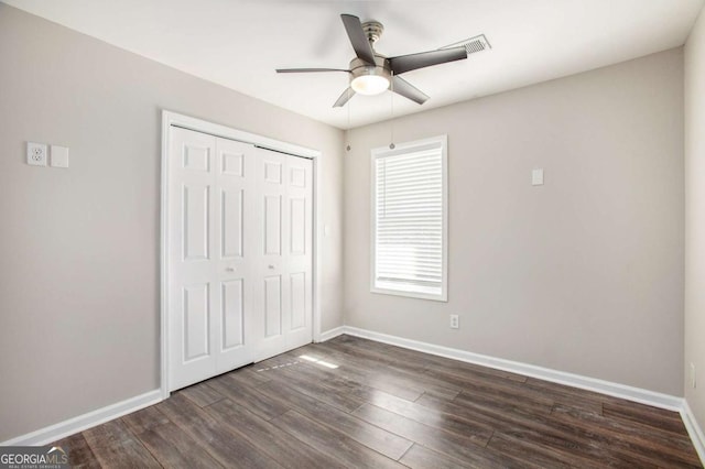 unfurnished bedroom with ceiling fan, dark wood-type flooring, and a closet