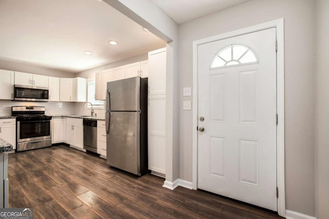 kitchen featuring white cabinetry, sink, stainless steel appliances, tasteful backsplash, and dark hardwood / wood-style flooring