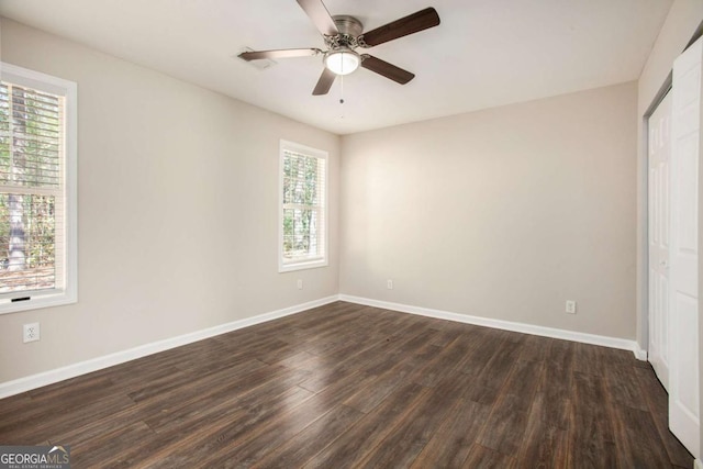 unfurnished bedroom featuring dark hardwood / wood-style floors, ceiling fan, a closet, and multiple windows