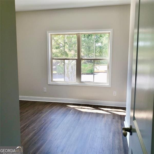 unfurnished room with plenty of natural light and dark wood-type flooring