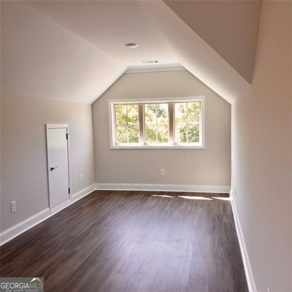 bonus room with dark hardwood / wood-style floors and vaulted ceiling