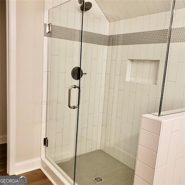 bathroom featuring wood-type flooring and a shower with shower door