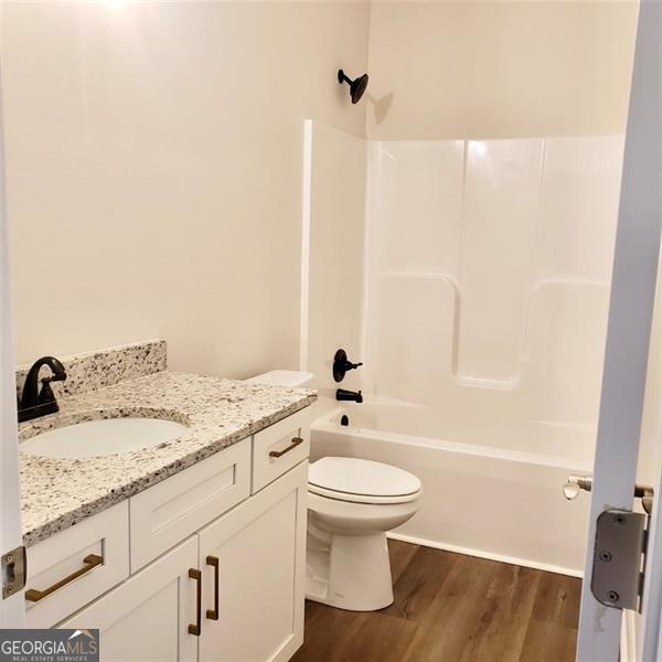 full bathroom with hardwood / wood-style flooring, vanity, toilet, and shower / bath combination