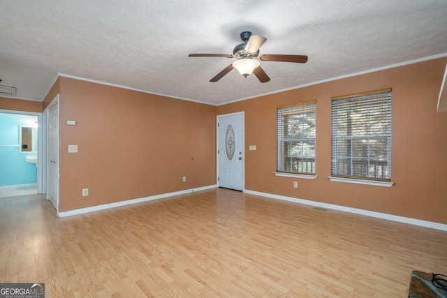 empty room with a textured ceiling, light hardwood / wood-style flooring, ceiling fan, and ornamental molding