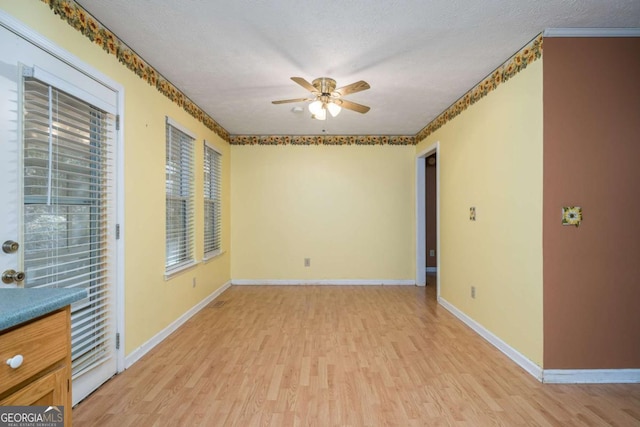 spare room featuring a textured ceiling, light wood-type flooring, a wealth of natural light, and ceiling fan